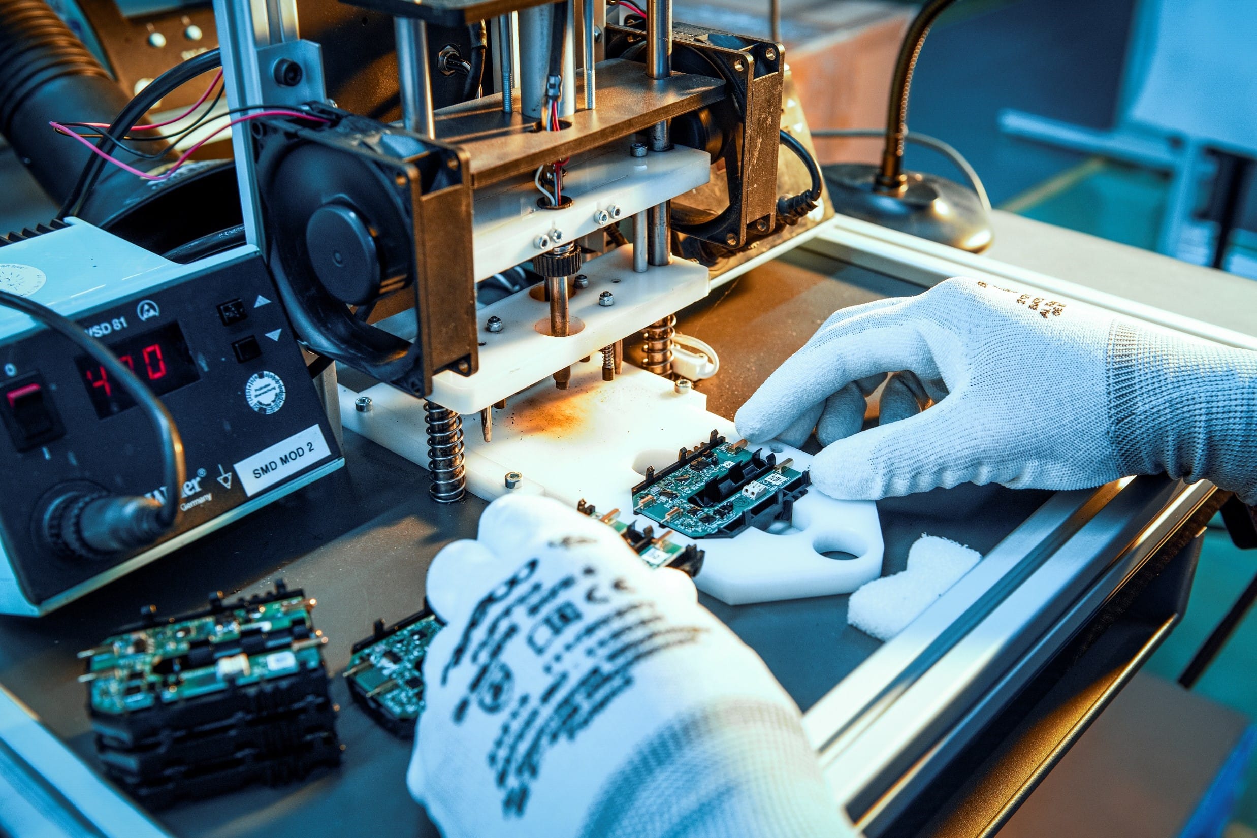 Box Build bei Variosystems: Eine Fachkraft legt eine Leiterplatte in eine Fertigungsstation ein.